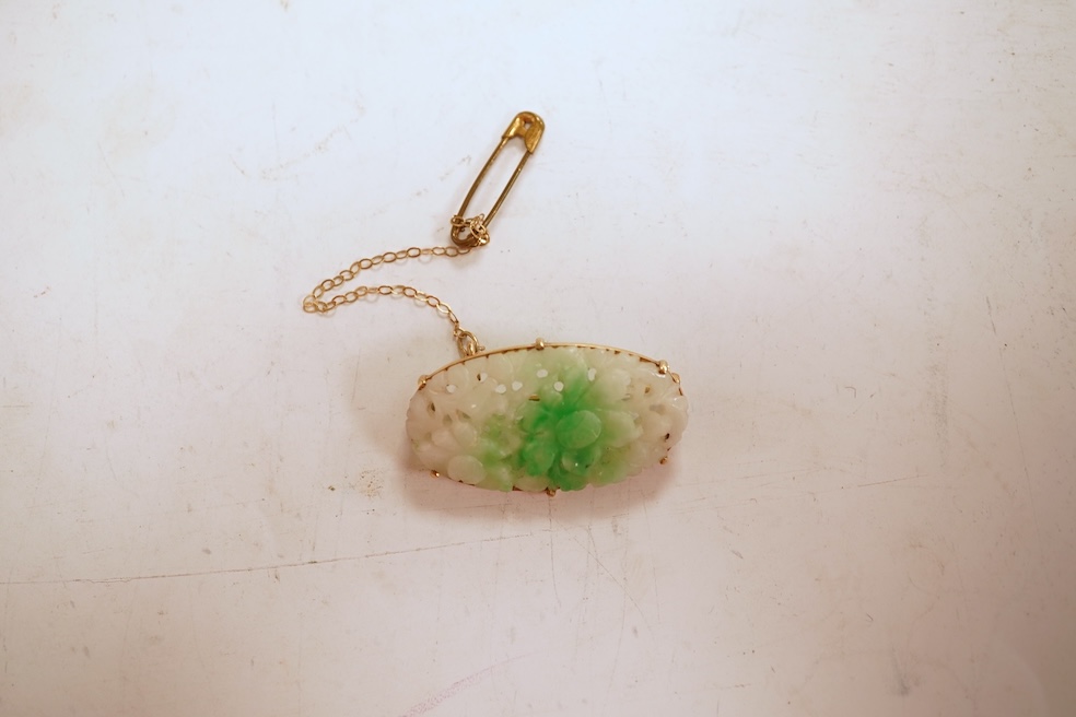 A jadeite brooch, set with an oval jadeite of mottled green and white, carved to depict flowers, mounted in 9ct gold, length 3.2cm, British hallmarks, maker's mark for Cropp & Farr, gross weight approximately 4.5 grams,
